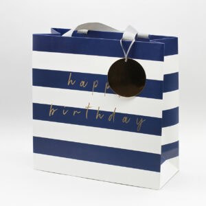 Colorful happy birthday gift bag with navy blue and white stripes, with "happy birthday" message in gold script, perfect for celebration or party favors.
