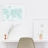 Minimalist white desk with elegant decor, including framed artwork, a candle, and potted plants, creating a calm and stylish workspace or home office setting.