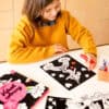 A girl coloring a Valentine’s Day-themed unicorn picture on black construction paper with markers, creating festive and romantic artwork for Valentine’s Day.