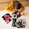 Coloring activity with black and white Valentine-themed coloring pages, markers, and colorful rainbow and unicorn designs for kids.
