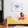 Yellow children’s bed with a girl reading a book, owl pillow, and colorful artwork in a modern kid’s room.