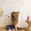 Colorful girl creating custom artwork on a large whiteboard at The Wraperie, a creative space for personalized wraps, murals, and artistic projects.