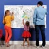 Coloring activity at The Wraperie, featuring a vibrant family engaging in creative arts with a large world map coloring poster, perfect for fun and educational family outings.