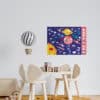 Colorful children's playroom with space-themed artwork on the wall, wooden chairs, a yellow rug, and playful décor for kids.