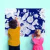 Coloring activity at The Wraperie, showcasing kids creating space-themed artwork on a large chalkboard wall with vibrant space and robot illustrations.