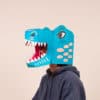 Colorful paper mache T-Rex head mask for dinosaur themed parties or costume accessories at The Wraperie. Unique, playful, and handmade dinosaur masks for kids and adults.