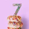 Sprinkles-covered donuts with a silver glitter number 7 candle on top, celebrating a birthday or special occasion. Colorful and festive treat perfect for celebrations.