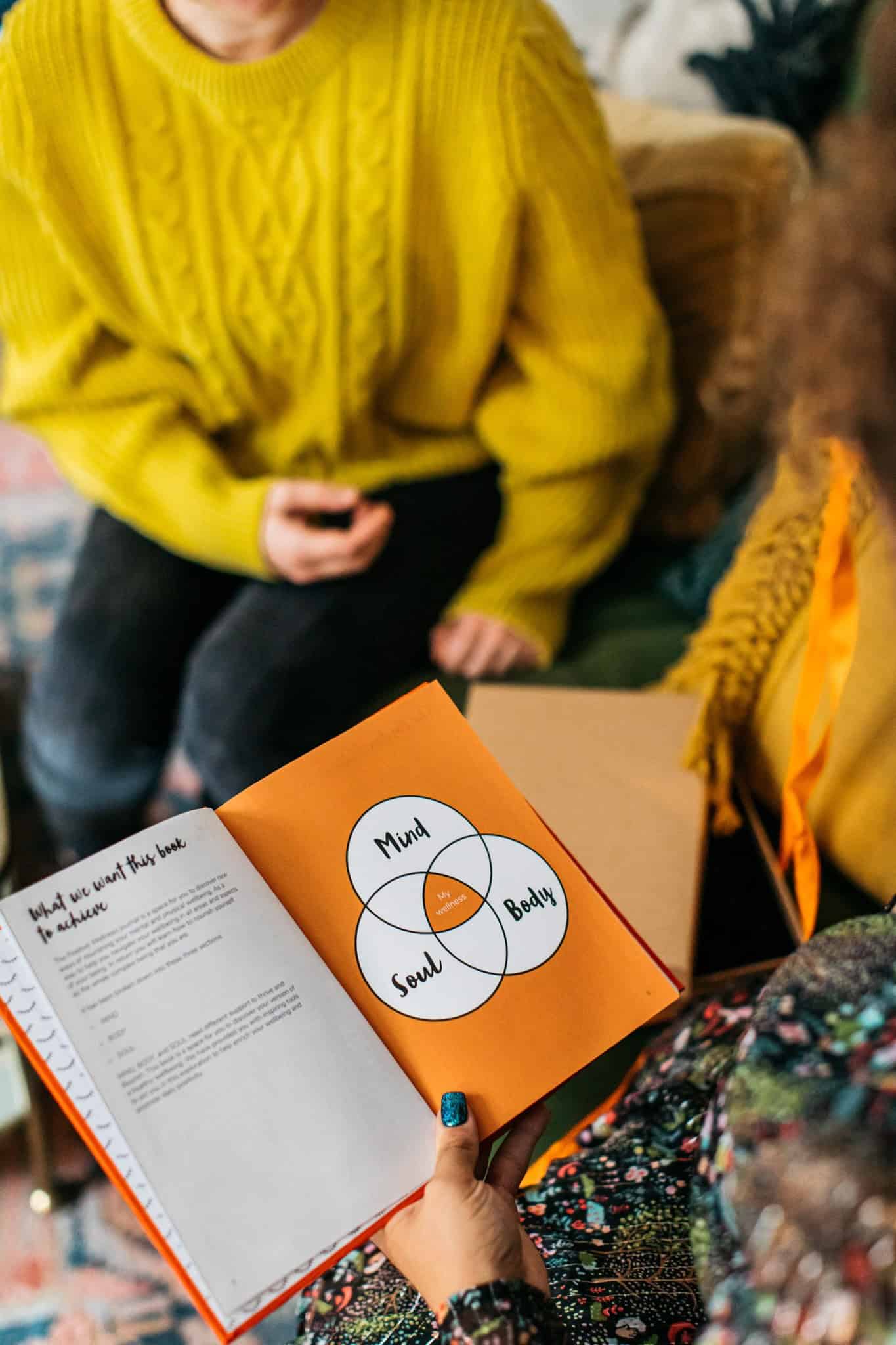 Vibrant yellow sweater worn by a person holding a phone inside a cozy cafe setting.