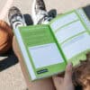A motivational workbook open on a person's lap with colorful pages and prompts for self-improvement, showcasing a focus on mental health and personal growth.