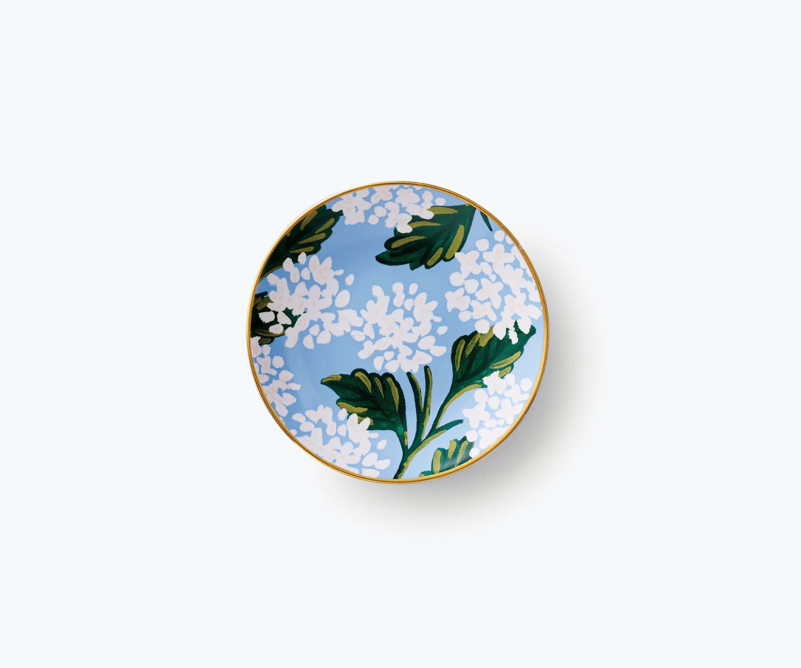 Colorful floral patterned plate with white flowers and green leaves on a blue background, edged with gold, designed for stylish food presentation and home decor.