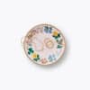 Delicate gold jewelry, including hoops and a pearl necklace, displayed on a colorful floral plate, showcasing elegant accessories for women. Perfect for gift ideas or stylish adornments.