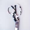Sharp scissors with a black and white abstract pattern on the handles, placed on a light background, perfect for arts, crafts, and sewing projects.