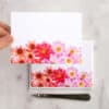 Vibrant floral-themed greeting cards featuring pink, red, and orange flowers, perfect for personalized messages and special occasions, displayed on a marble surface with a pen.