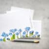 Vibrant blue forget-me-not flower greeting cards on textured white background, perfect for floral-themed stationery and personalized messages.