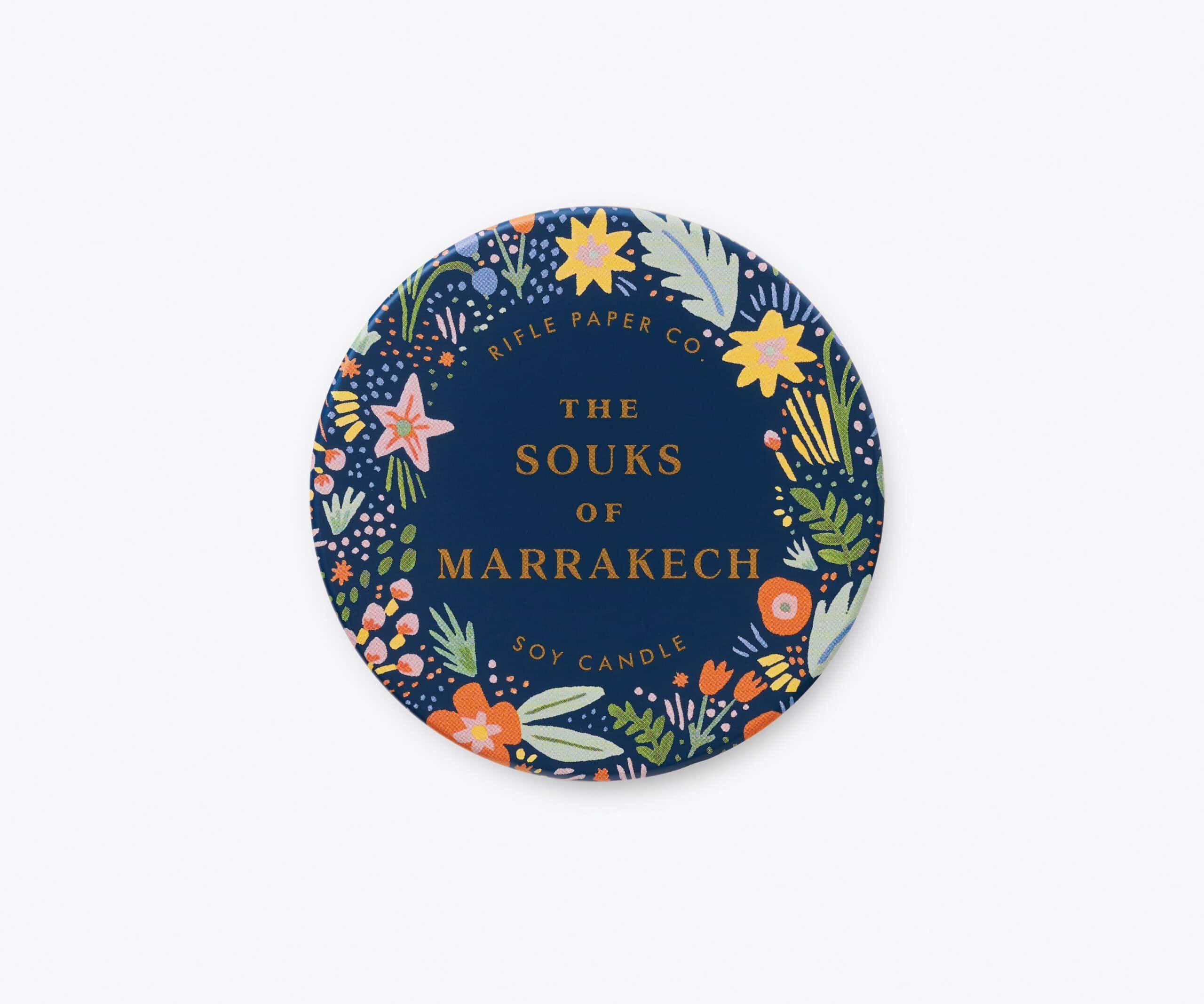 Vibrant round candle with floral design and the text "The Souks of Marrakech" on navy background, offering Moroccan-inspired decor and aromas.