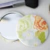 Colorful floral cosmetic mirror with compact design, perfect for on-the-go beauty touch-ups.