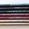 Black and maroon coffee stir sticks with humorous coffee-related quotes, designed for The Wraperie coffee shop, highlighting their specialty coffee accessories and fun brand personality.
