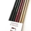 Black, red, and gold sharpened pencils with coffee-inspired quotes, perfect for coffee lovers, creative professionals, and office use, featured in The Wraperie gift set for writers and coffee enthusiasts.