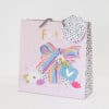 Colorful gift bag with polka dot, stripe patterns, floral accents, and a bow, from The Wraperie, perfect for gift wrapping and special occasions.