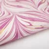 Vibrant pink and white marbled paper wrap with gold accents, ideal for gift wrapping or decorating.