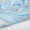 Vibrant blue, white, and beige marbleized pattern print on wrapping paper, ideal for gift wrapping and decorative crafts. Perfect for customized gift wraps at The Wraperie.