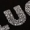 Wrapery logo with star-shaped glitter on black fabric, showing detailed embroidery and branding of The Wraperie restaurant and catering services in Orlando, Florida.