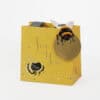 Colorful gift bag with bee and floral designs, perfect for special occasions or gifting, featuring a bright yellow background and decorative elements.