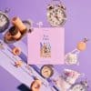 Delicious cookies and vintage clocks arranged on a pastel purple background, showcasing tea time essentials and elegant tableware for a stylish, cozy tea gathering.
