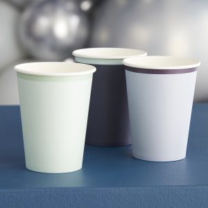Recyclable paper cups with black, white, and pastel-colored design on blue surface, used for beverages at The Wraperie.
