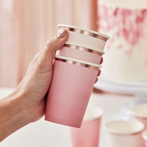 Pink paper cups with metallic gold accents, perfect for party gatherings or events at The Wraperie. Stylish, eco-friendly disposable cups for beverages.