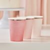 Pink paper coffee cups with white lids on a white surface at The Wraperie.
