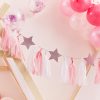 Bright pink and white hanging tassel and star decorations with balloons, perfect for birthday parties or celebration decor at The Wraperie.
