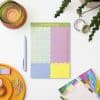 Bright colorful planner page with schedule and to-do list, surrounded by decorative stationery, washi tapes, and plants, perfect for organizing daily tasks at The Wraperie.