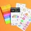 Brightly colored sheet of fun stickers, including smiley faces, rainbows, and positive phrases, from The Wraperie's super sticker club, perfect for decorating planners, notebooks, and creative projects.