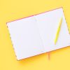Bright open notebook with lined pages and a yellow pen on a vibrant yellow background, ideal for journaling, planning, or note-taking.