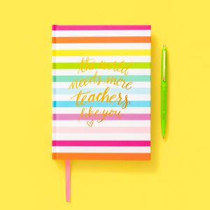 Colorful striped notebook with inspirational quote about teachers on the cover, accompanied by a green gel pen, on a vibrant yellow background, ideal for educational and motivational content.