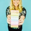 Bright smiling woman holding colorful motivational notepad, positive energy and encouragement, cheerful vibe, stationery, inspirational quotes, vibrant, uplifting office or home decor, healthy lifestyle.