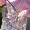 Shoppers holding a transparent, glitter-adorned tote bag with iridescent straps, showcasing stylish and functional accessories at The Wraperie. Perfect for carrying wraps and essentials efficiently.