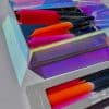 Vibrant colorful candles in holographic display box, modern aesthetic by The Wraperie, perfect for stylish home decor or gifts, featuring pink, orange, black, and other bright hues for a chic look.