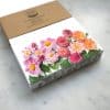 Colorful flower arrangement in a floral gift box, perfect for special occasions or gift-giving, showcasing vibrant pink and orange blooms with green foliage.