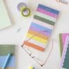 Colorful sticky notes and office supplies on a desk, featuring pastel shades and a playful design, perfect for organization and creative planning at The Wraperie.