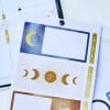 Gold and navy celestial-themed planner stickers with moon, star, and motivational quotes for organization and goal-setting. Perfect for bullet journaling and planner decor.