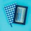 Bright blue and white checkered notebook with motivational quote, accompanied by a package of five blue ink pens with inspirational messages, perfect for journaling, note-taking, or office use.