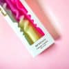 Pink and yellow swirl dipped candles in packaging, ideal for home decor and gifting, featuring colorful, twisted wax design.