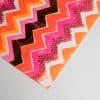 Vibrant colorful zigzag patterned wrapping paper with pink, orange, black, and gold accents, perfect for gift wrapping and celebrations.