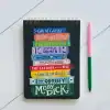 Books themed to classic literature including The Great Gatsby, Pride and Prejudice, Frankenstein, Little Women, and Moby Dick, arranged on a black notebook with colorful hand-lettered titles.