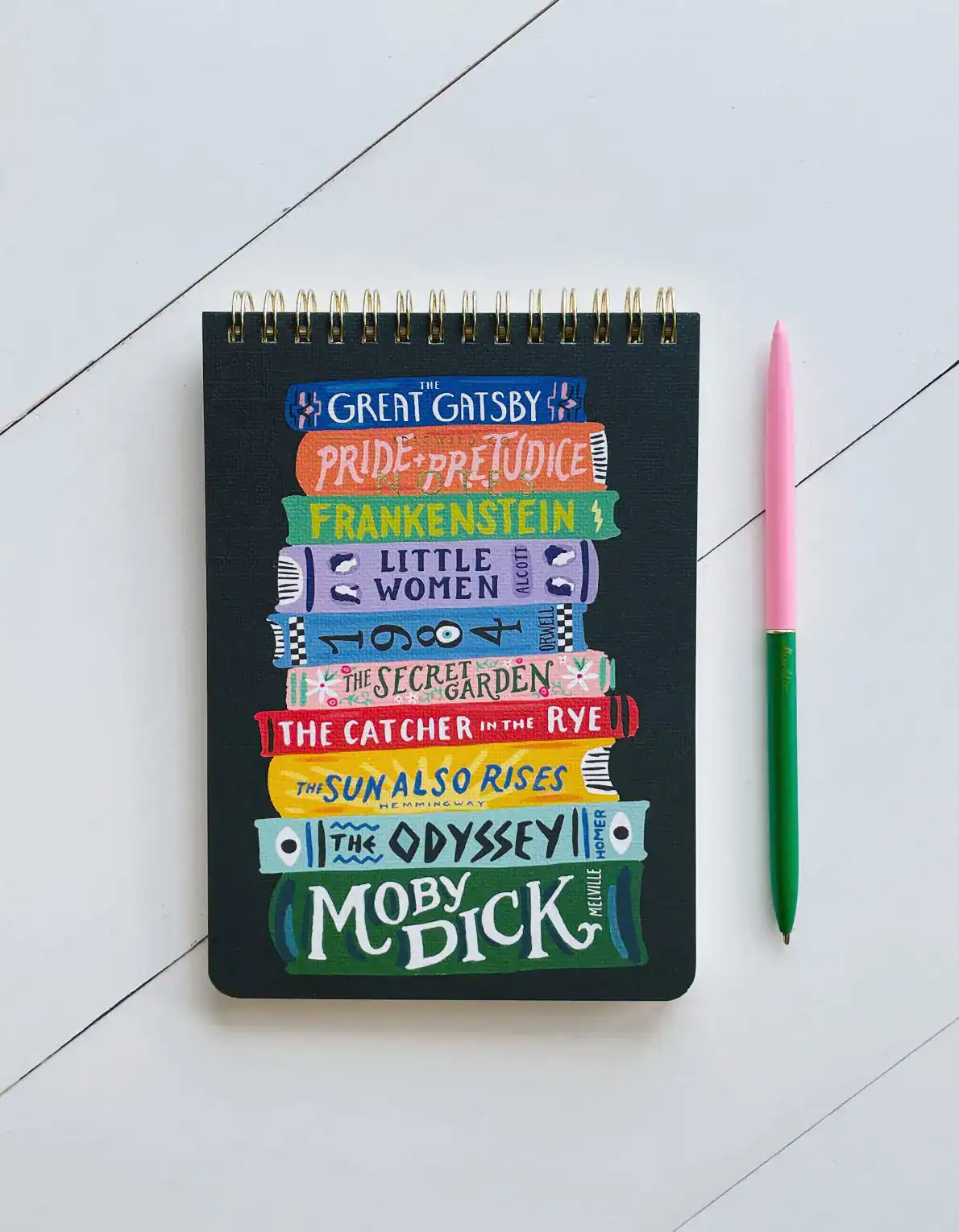 Books themed to classic literature including The Great Gatsby, Pride and Prejudice, Frankenstein, Little Women, and Moby Dick, arranged on a black notebook with colorful hand-lettered titles.
