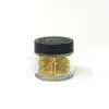 Gold paper clips in a clear storage jar with a black lid for organization and office supplies.