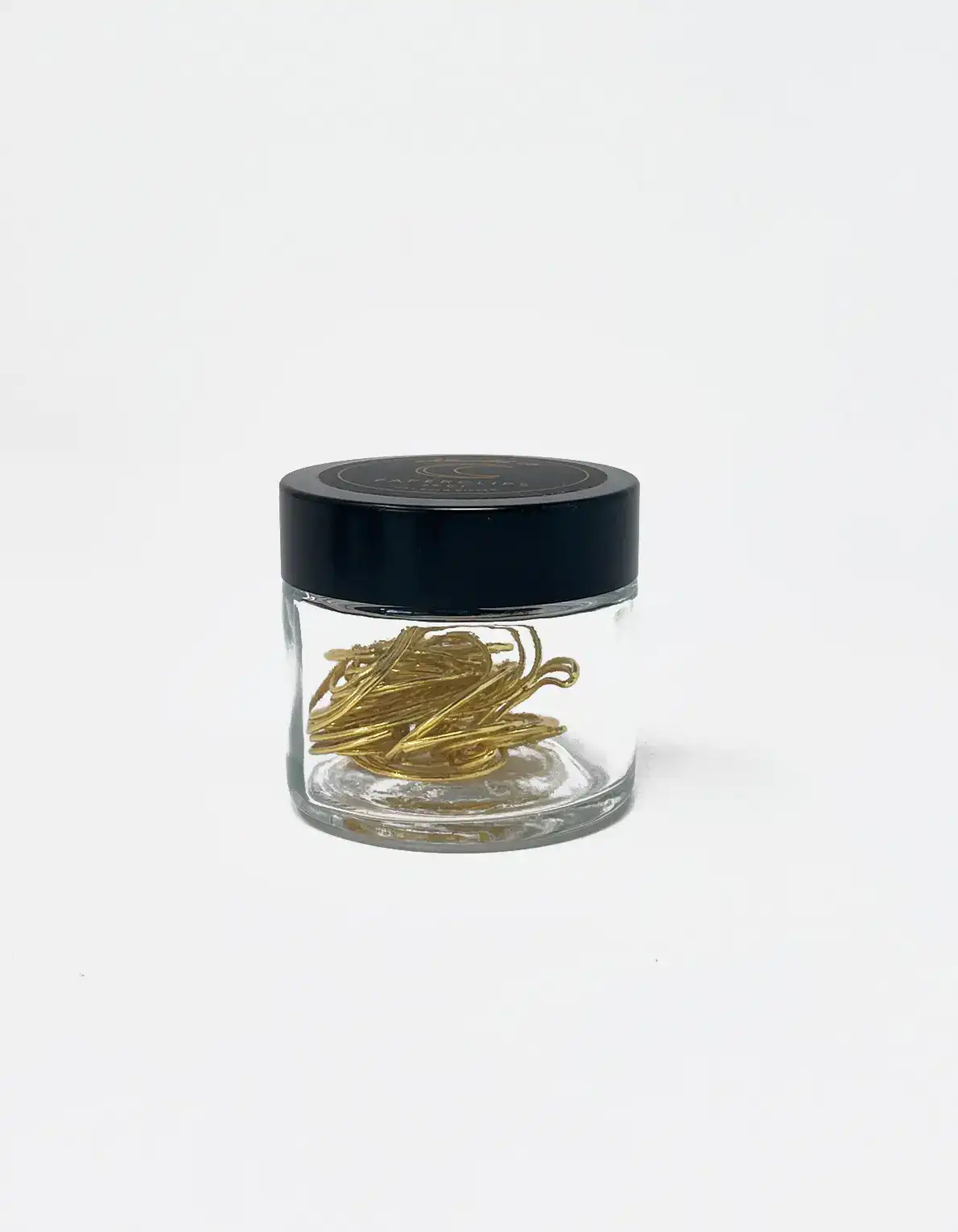 Gold paperclip storage jar with black lid, minimalist design for office or home organization, ergonomic and stylish storage solution for clips and small items in the workplace or living space, branded product from The Wraperie.