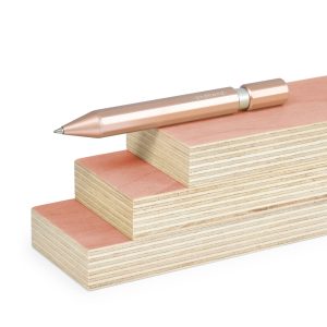 Sleek rose gold pen resting on stacked pastel-colored wooden blocks, minimalistic desk accessory, modern stationery, elegant writing tool with "andhand" branding.